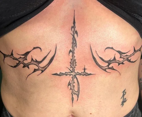Kreuz und ornamentale Motive am Bauch – Tattoo von Nancy bei Gestochen Scharf